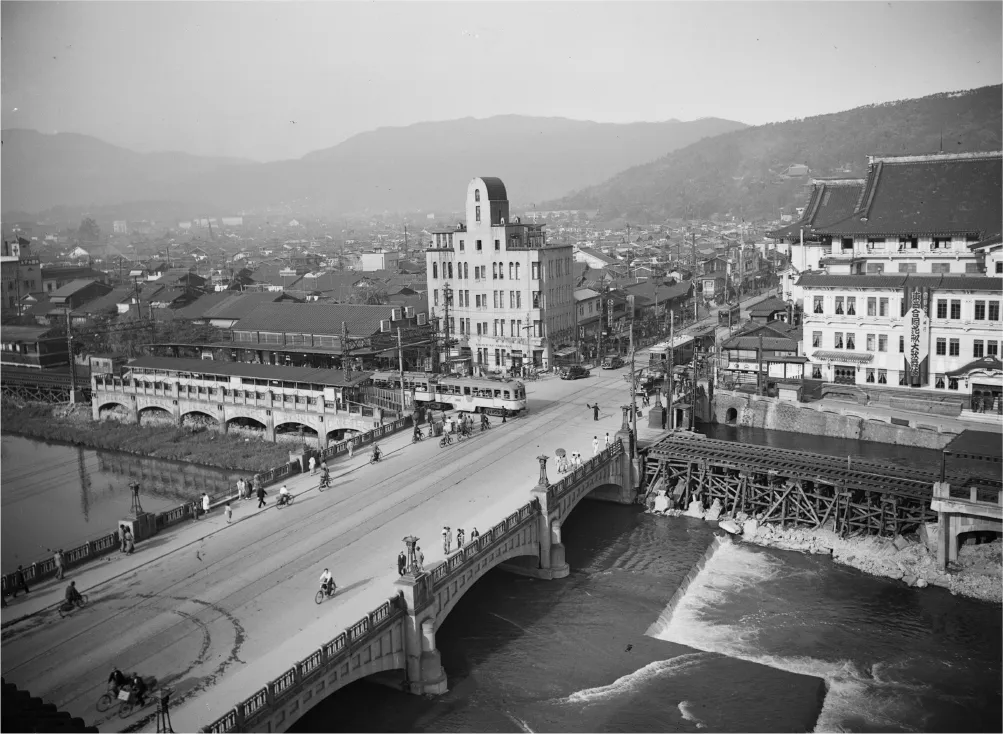 京阪電車の三条―五条間が開通したのは大正4年（1915年）。写真中央、四条大橋東で市電と京阪の線路が平面交差しているのがわかる。鴨川沿いの地上を電車が走る風景は昭和62年（1987年）まで続いた（黒川翠山撮影写真資料 京都府立京都学・歴彩館蔵）。